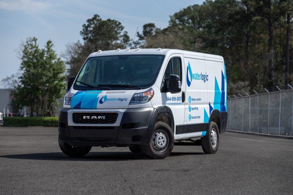 White and blue sprinter van with local business graphics.