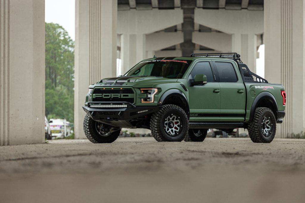 Green Ford Raptor truck with silver wheels.