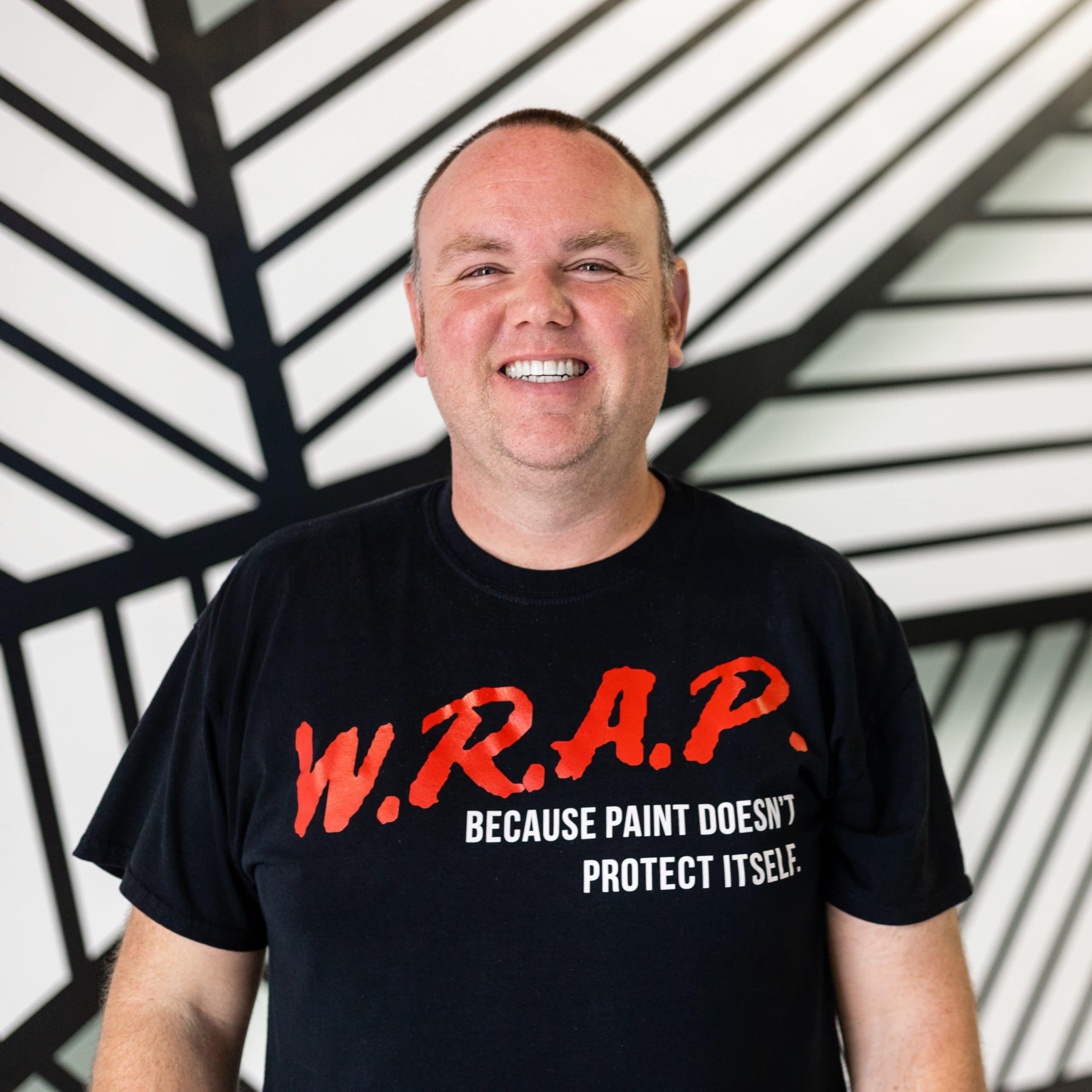 A man smiling with #201WRAP logo shirt.