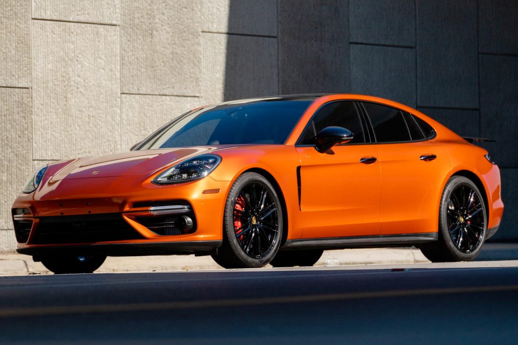 An orange Porsche with black wheels.