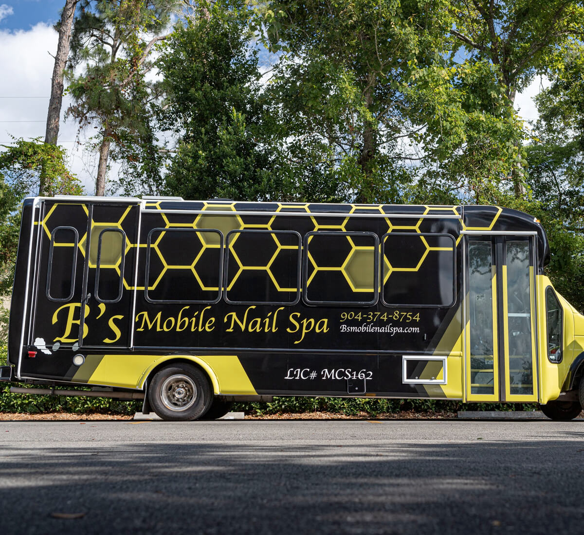 Yellow and black bus with nail spa business graphics.